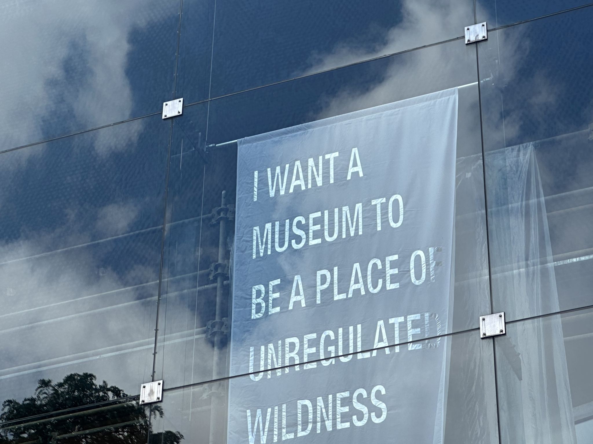 a banner in a windo that reads "I want a museum to be a place of unregulated wilderness"