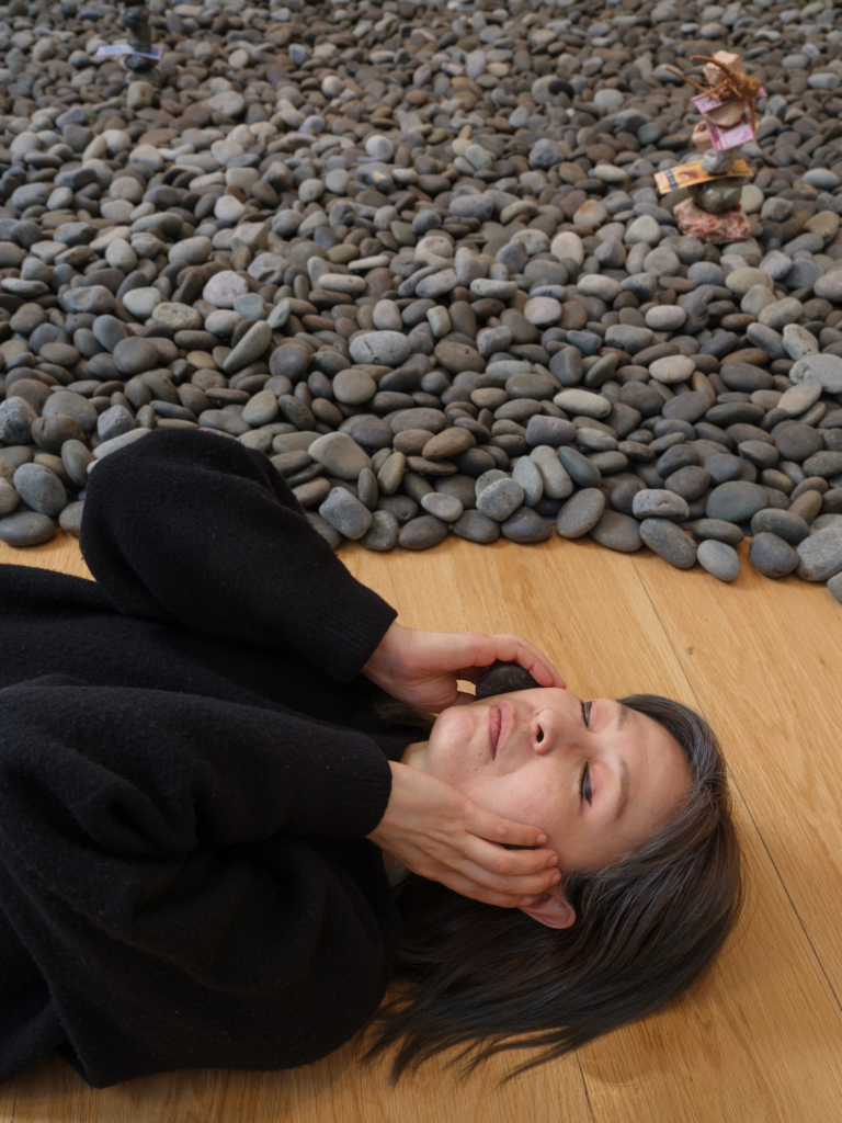 person laying amongst stones on a wooden floor