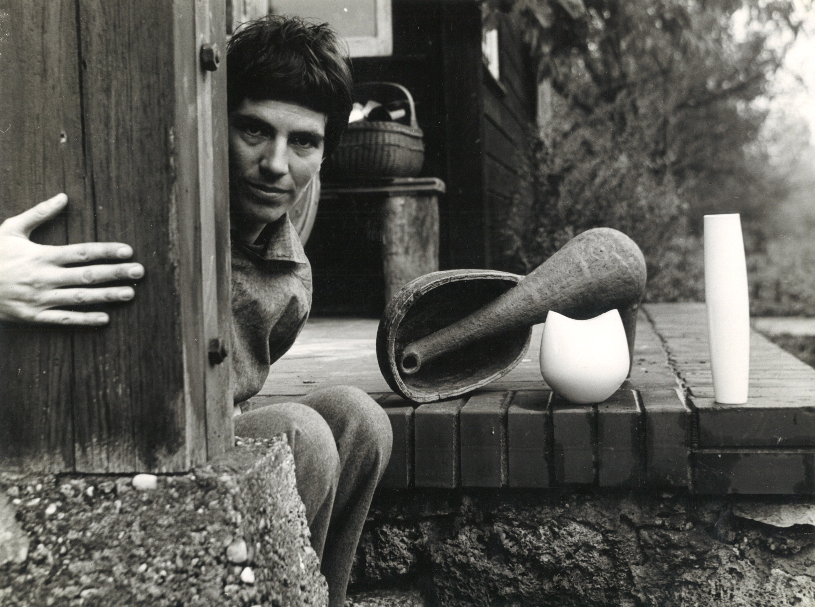 black and white photo of a man partially behind a wooden pillar