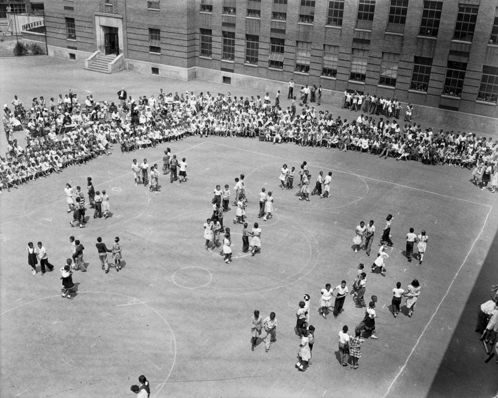 photograph of children giving square dancing demonstration in a school yard
