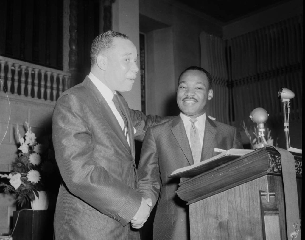 Charles Teenie Harris, Rev. Cornell Talley shaking hands with Dr. Martin Luther King Jr., at podium