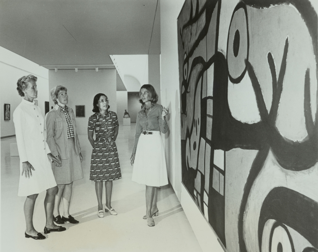 four women looking at art on a wall