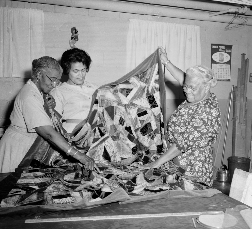 three women holding up a quilt