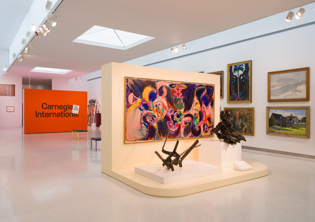 an art gallery with a red wall and many paintings