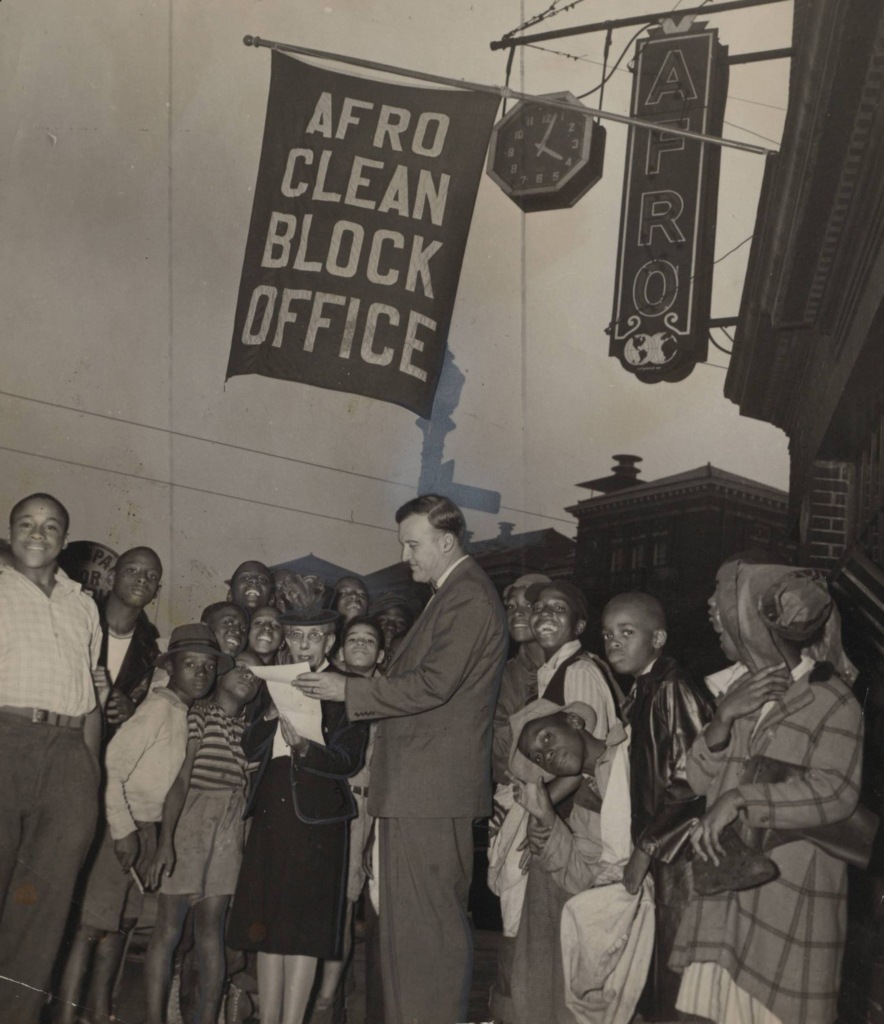 unidentified photographer, “Surrounded by excited AFRO newsies, Mayor McKeldin pauses in front of the AFRO building, Friday, while he and Miss Florence L. Murphy, Clean Block director, look over the route of the clean block tour of the city