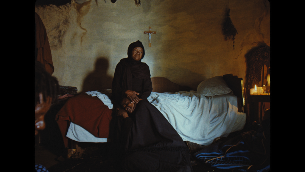 a film still of a man sitting beneath a cross