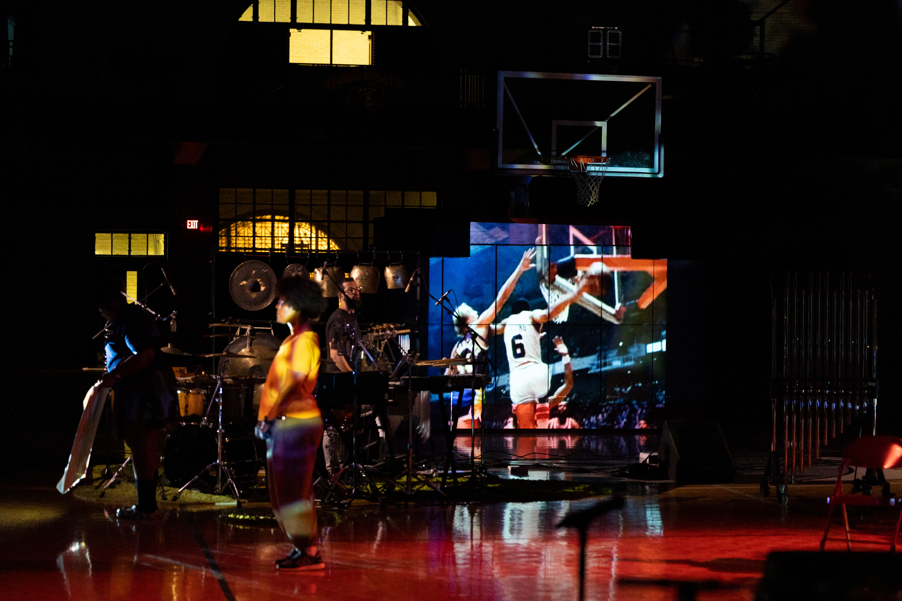 still of band and large panelled screen showing a basketball in the background