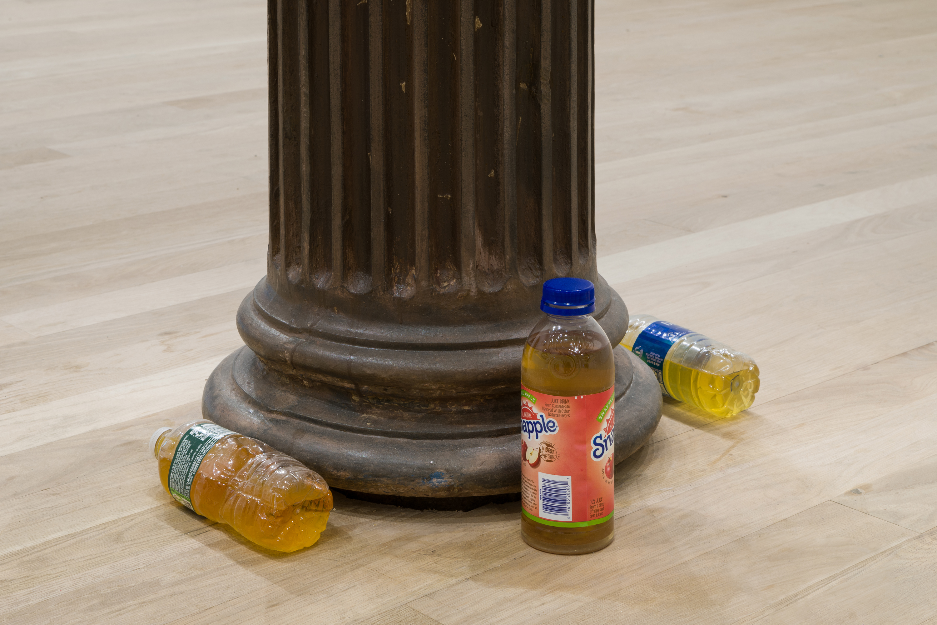 bottles of what I hope is apple juice in water bottles around a roman pillar