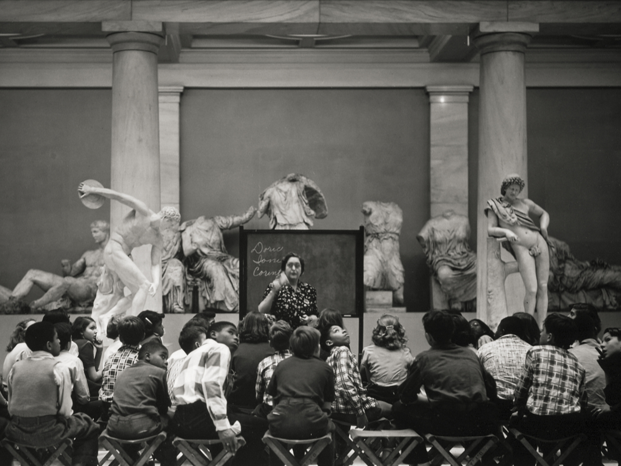 photograph of children learning from a teacher in the hall of architecture